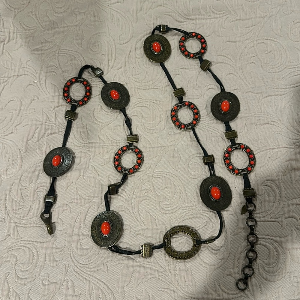 Brass like belt with orange detailing, around 56 inches long